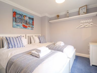 A bedroom with two single beds with striped pillows and folded towels on top at 23 Church Farm Lane in Halesworth