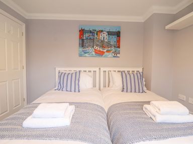 A bedroom with two single beds with striped pillows and folded towels at 23 Church Farm Lane in Halesworth