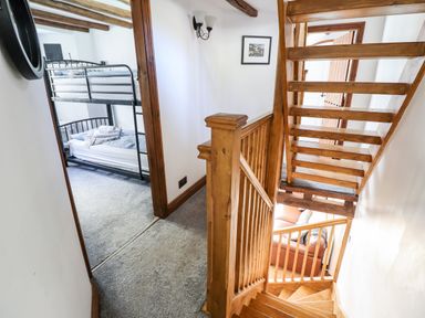 A hallway with wooden stairs and a room with bunk beds visible at Ty'n-Y-Ffynnon Cottage in Barmouth