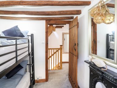 A bedroom with bunk beds wooden door and ceiling beams at Ty'n-Y-Ffynnon Cottage in Barmouth
