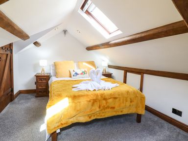 A bedroom with a bed covered with yellow bedding and two bedside tables with lamps at Ty'n-Y-Ffynnon Cottage in Barmouth