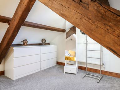 A room with white dresser and mirror with wooden beams on the ceiling at Ty'n-Y-Ffynnon Cottage in Barmouth