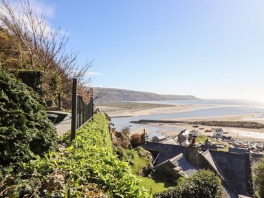 A seaside view with rooftops a river and a sandy beach at Ty'n-Y-Ffynnon Cottage in Barmouth