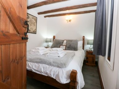 A bedroom with a bed and towels at Ty'n-Y-Ffynnon Cottage in Barmouth