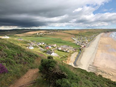 A coastal landscape with houses near a beach and green fields at Ty Rhosyn in Penycwm near Solva