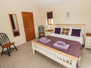 A bedroom with a double bed two chairs a mirror and bedside tables at Ty Rhosyn in Penycwm near Solva