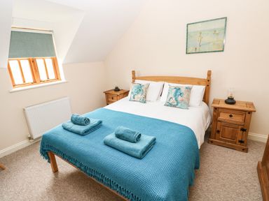 A bedroom with a double bed with blue blankets and pillows with sea creatures beside wooden nightstands at Ty Rhosyn in Penycwm near Solva