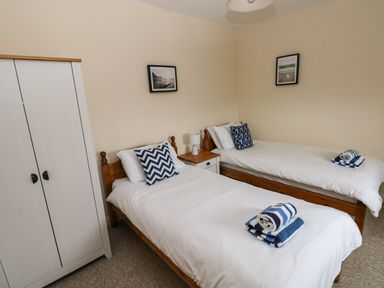 A bedroom with two single beds a white wardrobe and a bedside table at Ty Rhosyn in Penycwm near Solva