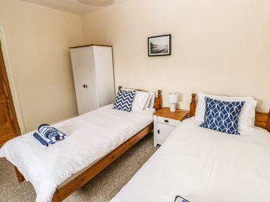 A bedroom with two single beds a white wardrobe bedside table and lamp at Ty Rhosyn in Penycwm near Solva