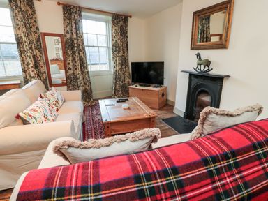 A sitting room with two sofas a wooden coffee table a television on a wooden chest and a fireplace at Upper Oakwood in Alnwick