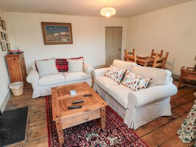 A living room with two white sofas and a wooden coffee table on a patterned rug at Upper Oakwood in Alnwick