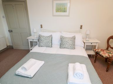 A bedroom with a double bed with patterned cushions and folded towels on a quilt at Upper Oakwood in Alnwick