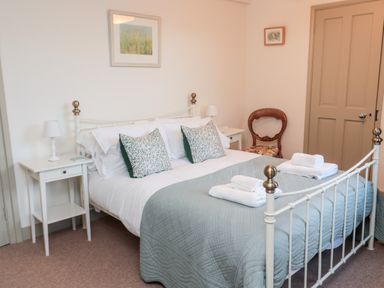 A bedroom with a metal bed frame two bedside tables with lamps folded towels on the bed and a wooden chair at Upper Oakwood in Alnwick