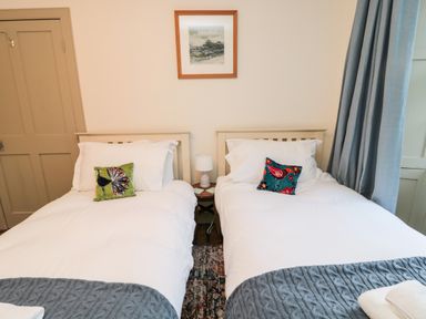 A bedroom with two single beds with white bedding and decorative cushions at Upper Oakwood in Alnwick