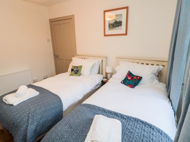 A bedroom with two single beds with white bedding and blue blankets at Upper Oakwood in Alnwick