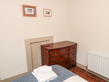A corner of a bedroom with a wooden chest of drawers white radiator and two framed pictures at Upper Oakwood in Alnwick