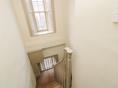 A staircase with a banister, a window with shutters, and walls painted white at Upper Oakwood in Alnwick