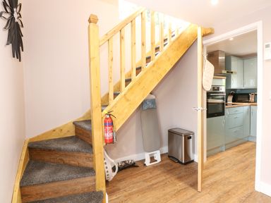 A staircase with carpeted steps next to a kitchen with blue cabinets and wooden floor at Strawberry Fields Annex in Emneth