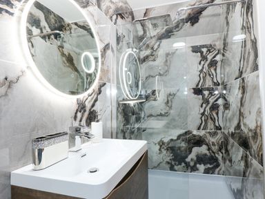 A bathroom with a sink vanity and a circular illuminated mirror above it and a walk-in shower with patterned wall tiles at Strawberry Fields Annex in Emneth