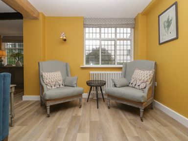 A sitting area with two armchairs and a small round table between them under a window at Byways in Madresfield near Malvern