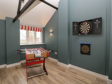 A game room with a foosball table and two dartboards on the wall at Byways in Madresfield near Malvern