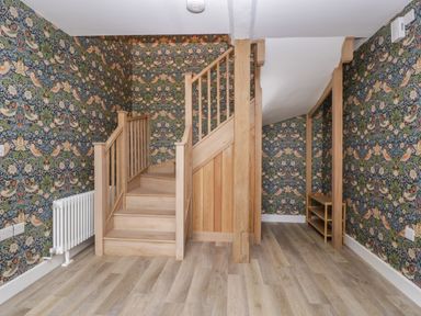 A stairwell with wooden stairs and floral patterned wallpaper at Byways in Madresfield near Malvern