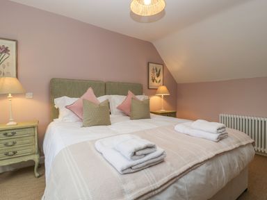 A bedroom with a double bed bedside tables lamps and folded towels at Byways in Madresfield near Malvern