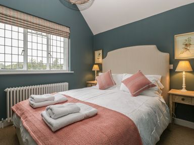 A bedroom with a double bed two bedside tables lamps and folded towels on the bed at Byways in Madresfield near Malvern