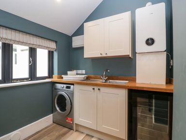 A utility room with a washing machine sink cabinets and a water heater at Byways Madresfield near Malvern