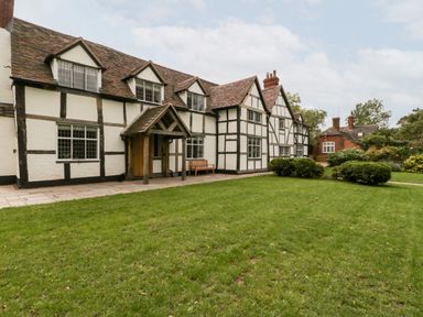 A large white and black timber framed house with a pitched roof and green lawn in front at Byways in Madresfield near Malvern