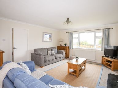 A living room with two sofas a wooden coffee table wooden furniture and a television at 7 Maes Awel in Abersoch