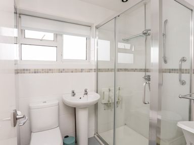 A bathroom with a toilet sink and glass shower enclosure at 7 Maes Awel in Abersoch