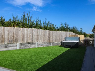 A garden with a hot tub and grass at 7 Maes Awel in Abersoch