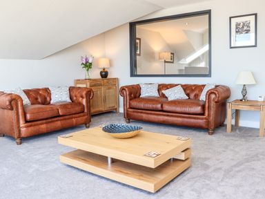 A living room with two leather sofas a wooden coffee table and lamps at The Waves in Amble