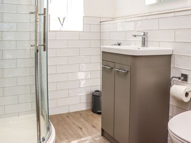 A bathroom with a shower enclosure sink cabinet and toilet paper holder at The Waves in Amble