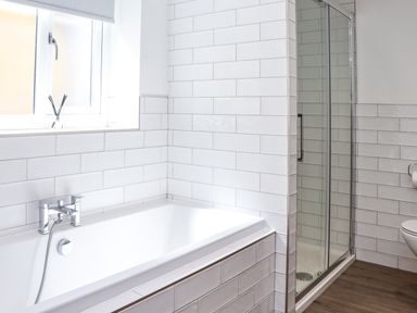 A bathroom with a bathtub a shower enclosure a window and a toilet at The Waves in Amble