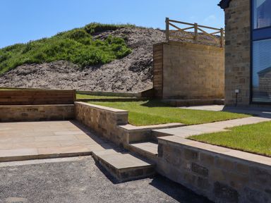 An outdoor area with stone steps grass and a wooden fence near a building at The Waves in Amble
