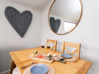 A dining area with a wooden table set for two with plates wine glasses and a charcuterie board at Fawn's Rest Nantmel near Rhayader