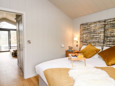 A bedroom with a bed holding breakfast on a tray bedside table and an open door showing an adjoining room at Fawn's Rest in Nantmel near Rhayader