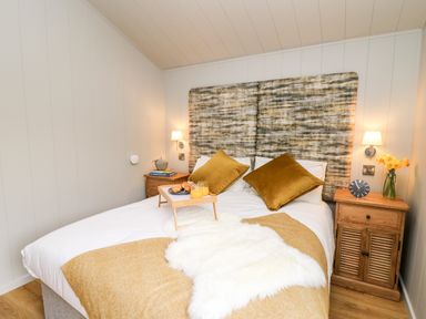 A bedroom with a double bed two wooden nightstands and a breakfast tray at Fawns Rest in Nantmel near Rhayader