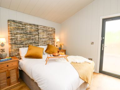 A bedroom with a bed with pillows and breakfast tray next to a window at Fawn's Rest in Nantmel near Rhayader