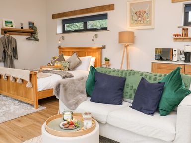 A bedroom with a wooden bed and a couch with cushions and a tray with food and drinks at Tin Shed in Nantmel near Rhayader