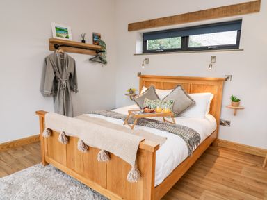 A bedroom with a wooden bed and breakfast tray near a small window at Tin Shed in Nantmel near Rhayader