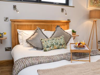 A bedroom with a wooden bed frame pillows and a tray with pancakes and glasses of orange juice at Tin Shed in Nantmel near Rhayader