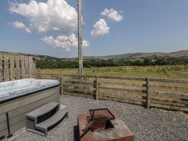 An outdoor area with a hot tub and fire pit at Tin Shed in Nantmel near Rhayader