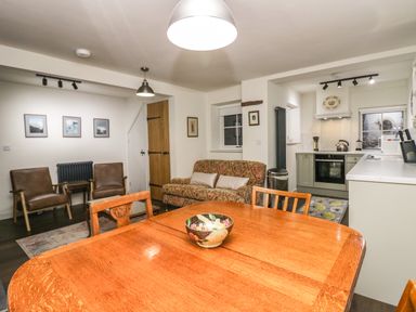 A kitchen and dining area with wooden table chairs sofa and two armchairs at Church How Cottage in Nether Wasdale