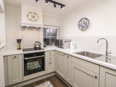 A kitchen with an oven sink microwave kettle and decorative plates on the wall at Church How Cottage in Nether Wasdale