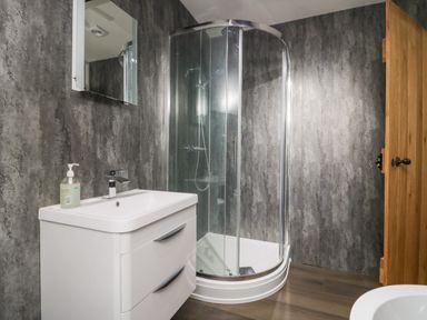 A bathroom with a white sink and mirror and a glass shower enclosure at Church How Cottage in Nether Wasdale