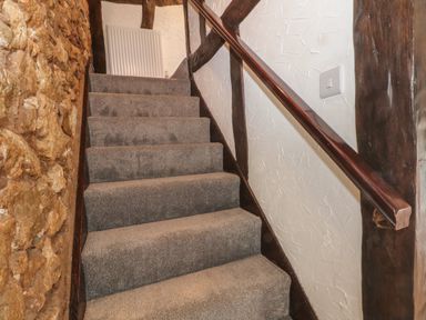 A carpeted staircase with wooden handrail and stone wall at The Coach House in Trelogan Hall Trelogan near Trelawnyd