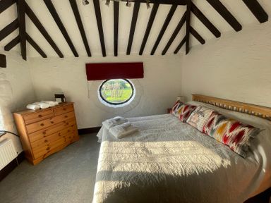 A bedroom with a wooden bed and chest of drawers under a ceiling with dark wooden beams at The Coach House in Trelogan Hall Trelogan near Trelawnyd